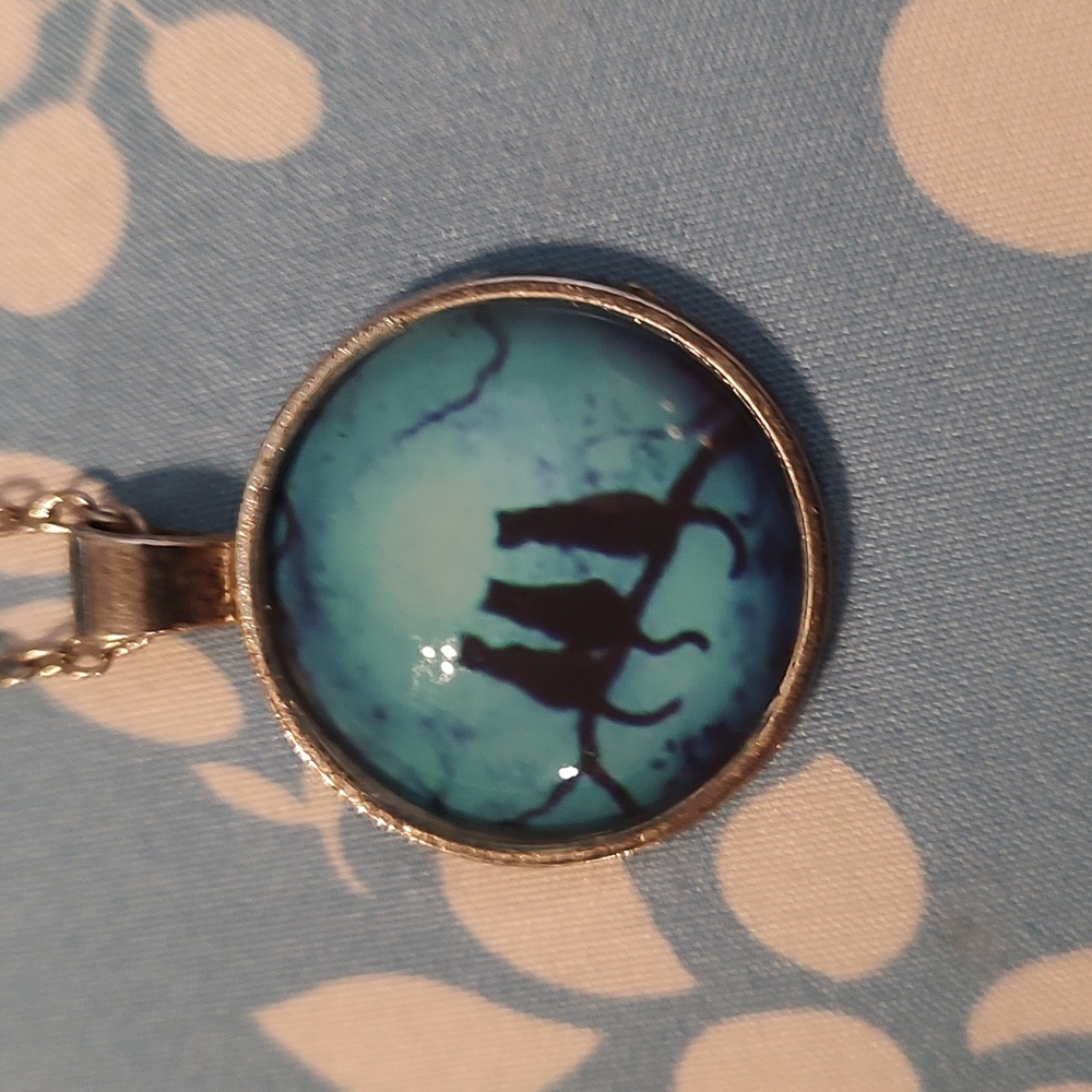 Women's necklace that has pendant with three cats sitting on a branch.